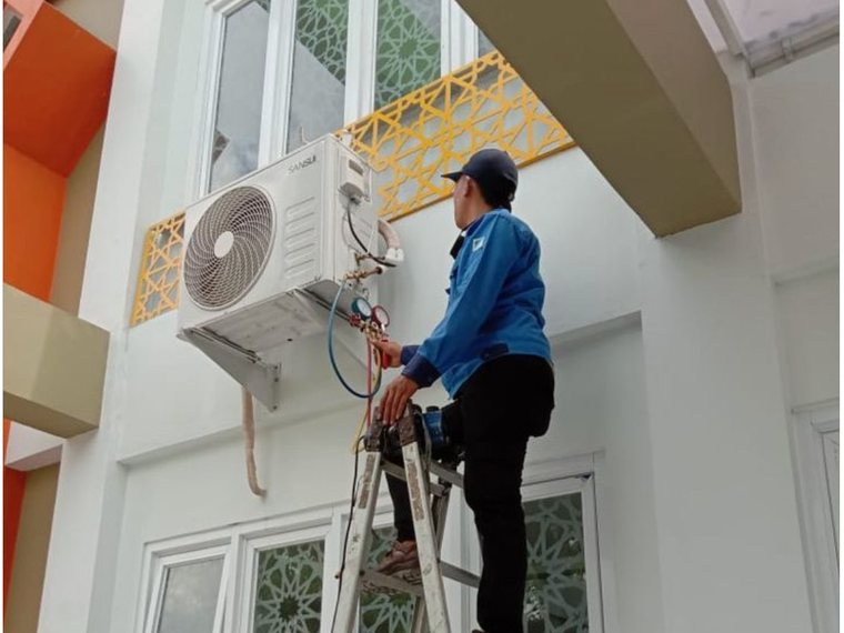 Pemasangan unit outdoor AC split pada dinding rumah di Tangerang Selatan