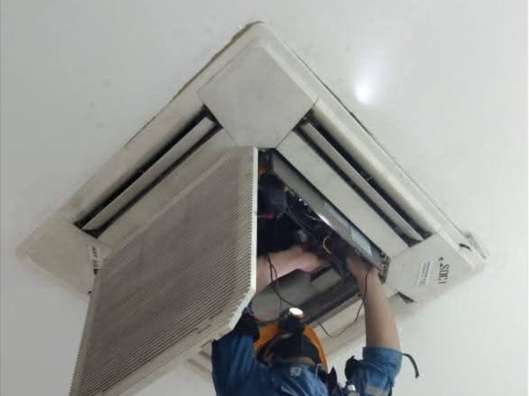 Teknisi memperbaiki AC cassette tertanam di plafon ruang usaha Bekasi